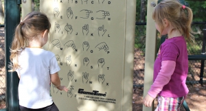 Fotografía de dos niñas mirando un panel con señas y su significado en el lenguaje de señas