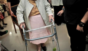 Imagen de una persona mayor con andador acompañada.