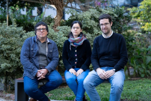 Nicolás Rodriguez junto a dos personas más, sentados en un banco del patio de facultad de psicología