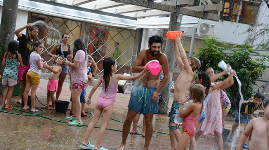 Fotografía de niños y sus recreadores jugando a la "guerra de agua" en el patio de la Facultad