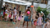 Fotografía de niños y sus recreadores jugando a la "guerra de agua" en el patio de la Facultad